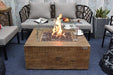 Backyard Lifestyles Modeno - Wilton Fire Table in Redwood front view of fire table on a deck surrounded by patio furniture with flame